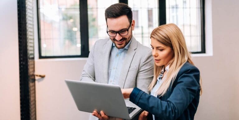 Young business man holding a laptop while discussing new project with his female colleague