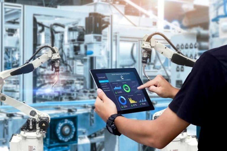 Employee holding tablet with dashboard display in front of machines