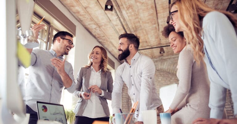 Team of employees in office surrounding table to discuss strategy