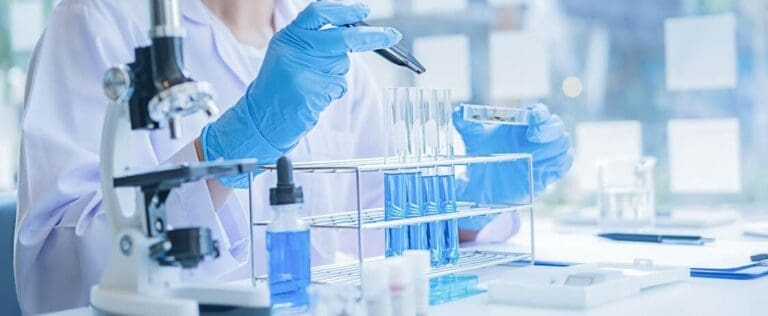 Medical or bioscienctific researcher looking at a test tube of clear solution in a laboratory