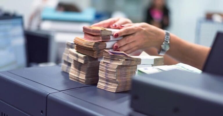 Bank or credit union employees sorting and counting money inside vault.