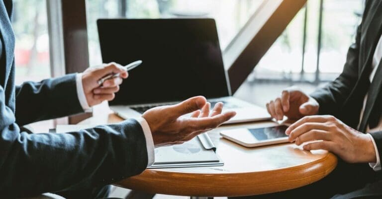 Two business people in consulting meeting with laptop and reports on the table in office