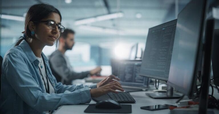 IT programmer writing code on computer in office