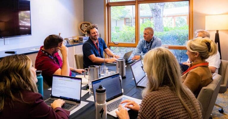 Consulting employees meeting around table with laptops, discussing ideas