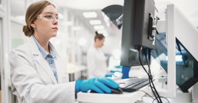 Laboratory technician at research & development company enters data into modern equipped computer