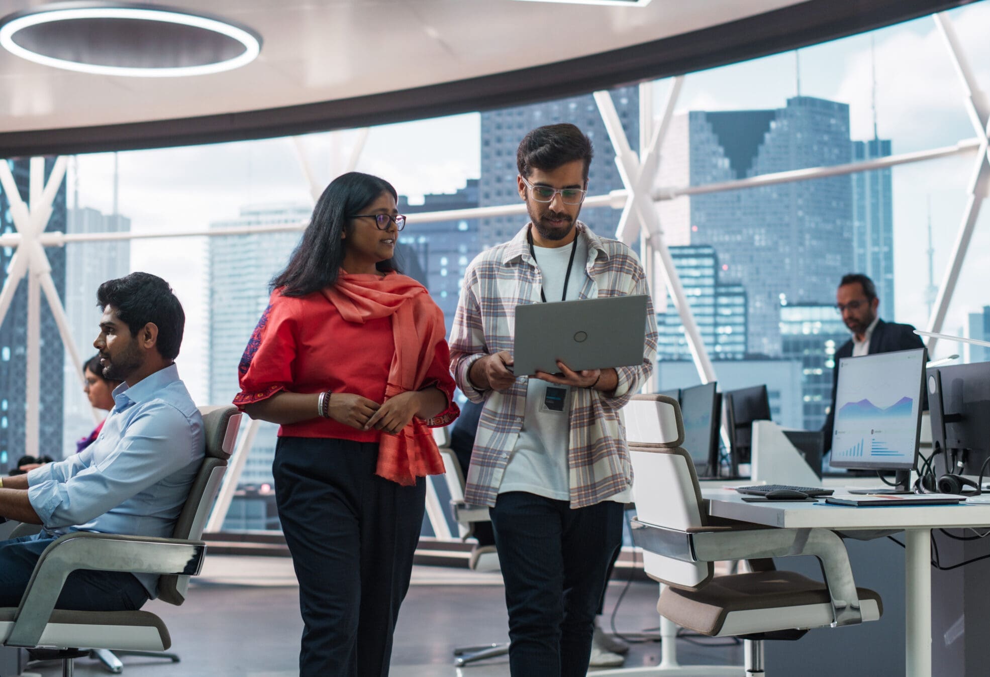 Young Team of South Asian Specialists Working on Desktop Computers at a Modern Workplace. Indian Software Developer Discussing a Financial Software Project with a Female Team Leader