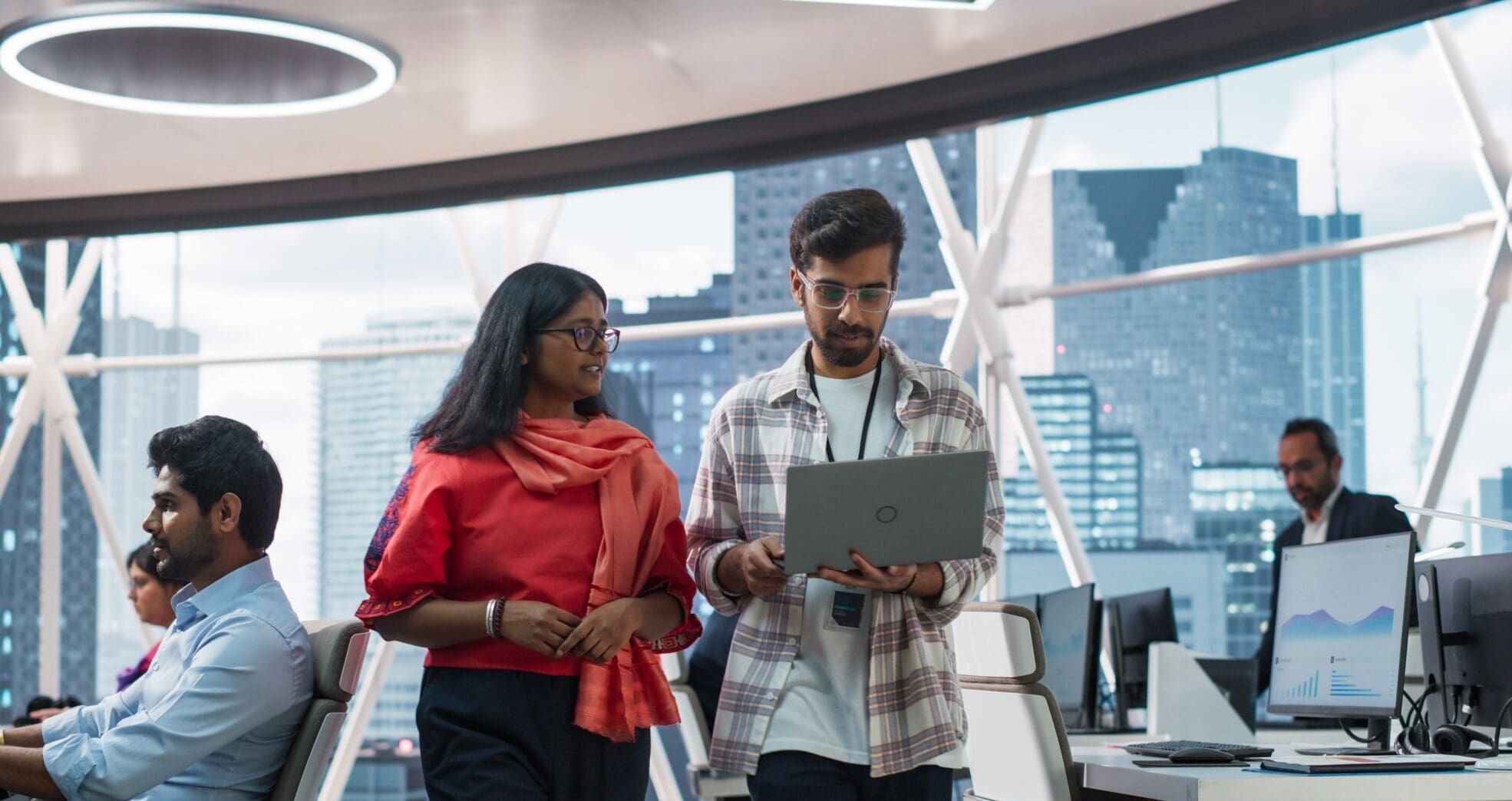 Young Team of South Asian Specialists Working on Desktop Computers at a Modern Workplace. Indian Software Developer Discussing a Financial Software Project with a Female Team Leader